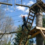 brave kid climbing in adventure rope park outdoors at summer day