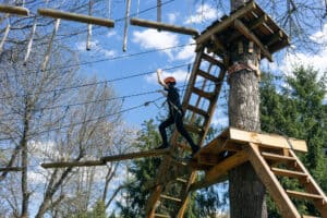 brave kid climbing in adventure rope park outdoors at summer day