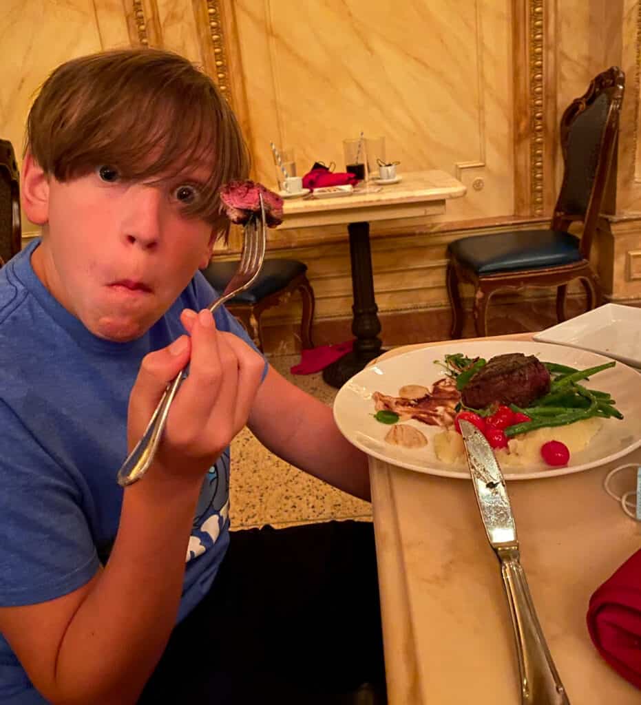 teen boy kaiden eating steak at a restaurant